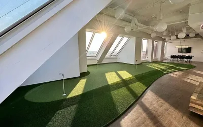 Indoor putting green installation in modern office space with natural light and curved design